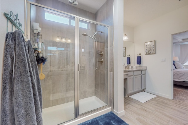 bathroom with hardwood / wood-style flooring, a shower with door, and vanity