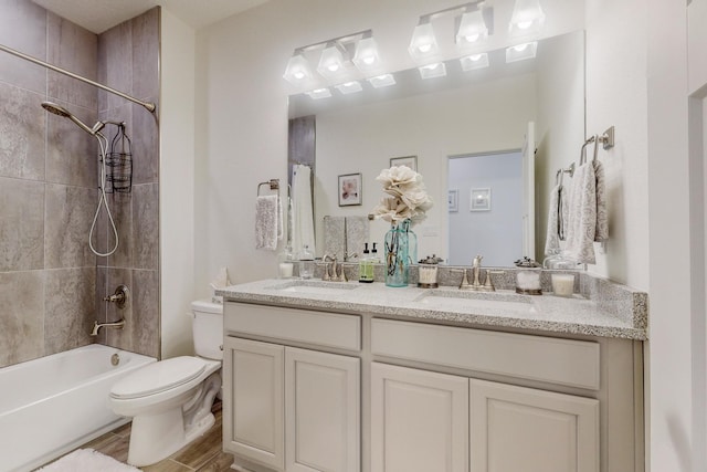 full bathroom featuring tiled shower / bath combo, vanity, and toilet