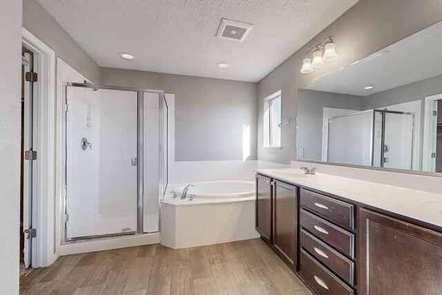 bathroom featuring a textured ceiling, separate shower and tub, and vanity