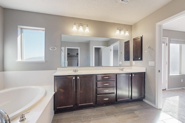 bathroom featuring a textured ceiling, a bathtub, and vanity