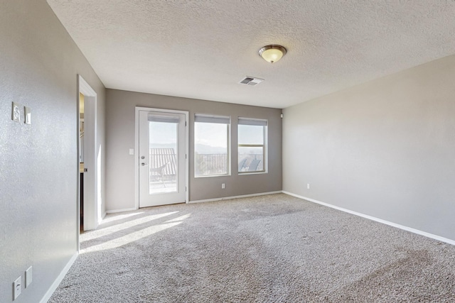 unfurnished room with a textured ceiling and carpet flooring