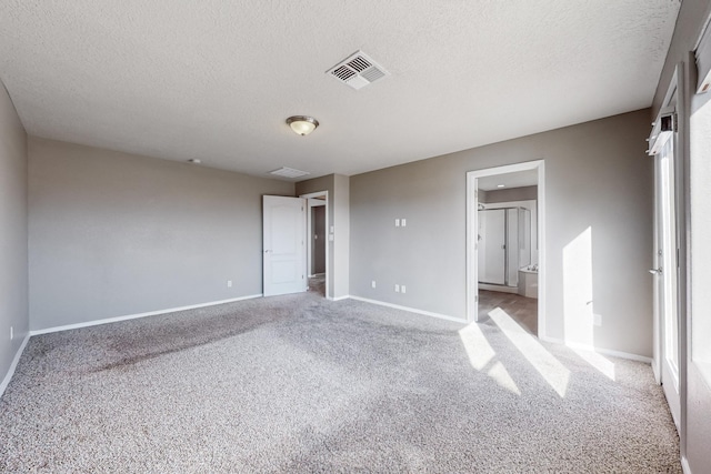 unfurnished bedroom with a textured ceiling, ensuite bathroom, and light carpet