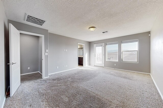 empty room featuring a textured ceiling and carpet flooring