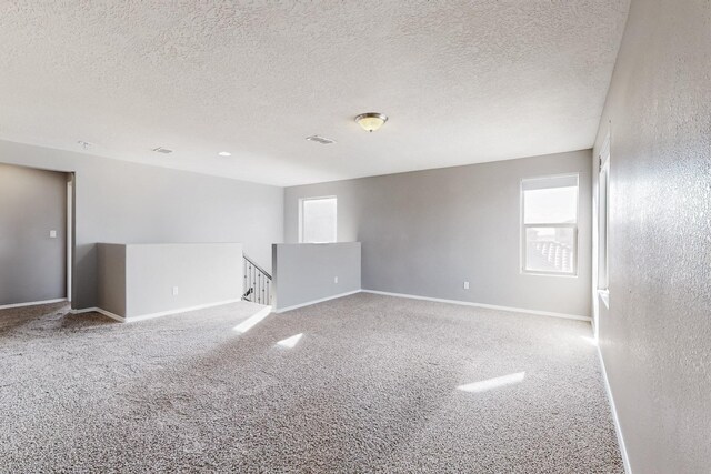 carpeted spare room with a textured ceiling