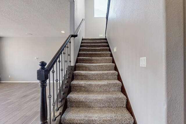 stairway featuring a textured ceiling and hardwood / wood-style flooring