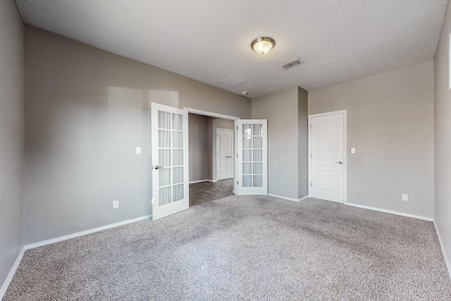 carpeted empty room featuring a textured ceiling and french doors