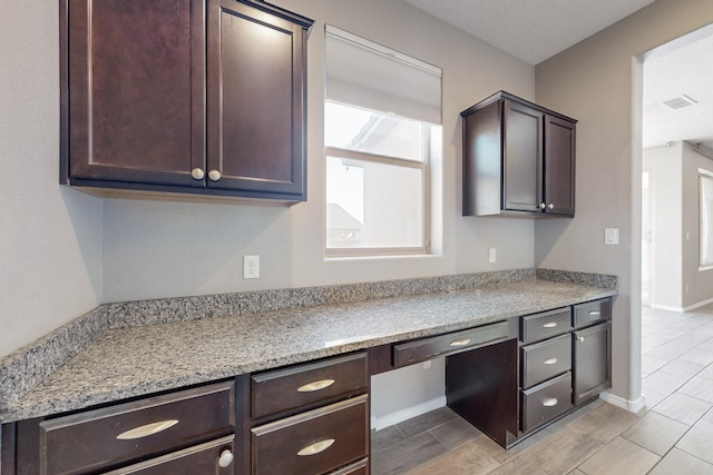 kitchen with a wealth of natural light, built in desk, and light stone countertops