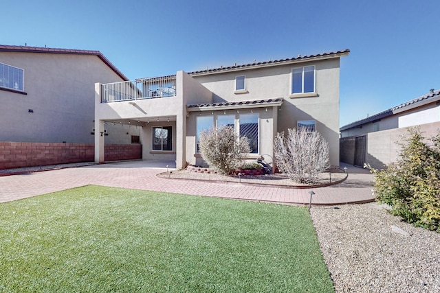 rear view of property with a lawn and a balcony