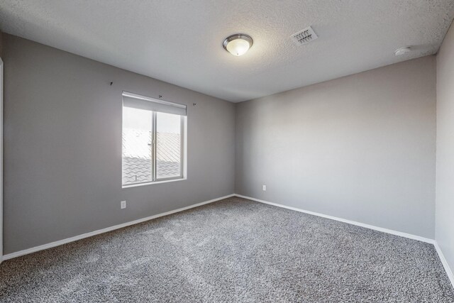 unfurnished room featuring a textured ceiling and carpet