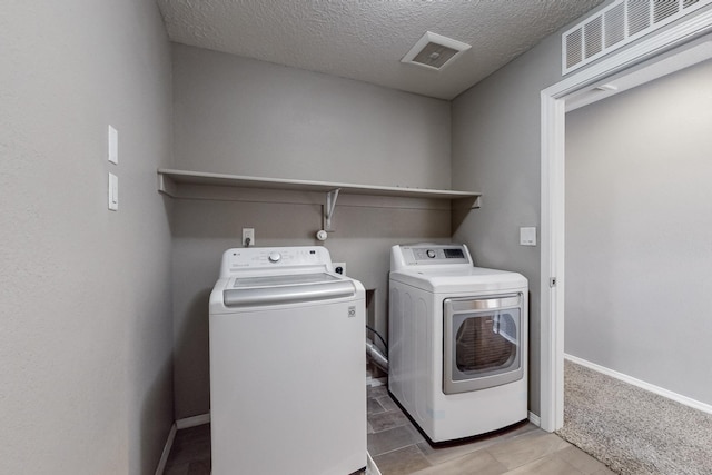 laundry room featuring a textured ceiling and washer and dryer