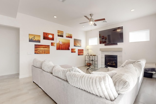 living room with a fireplace, ceiling fan, and light wood-type flooring