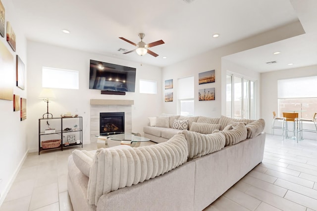 living room with a tiled fireplace and ceiling fan