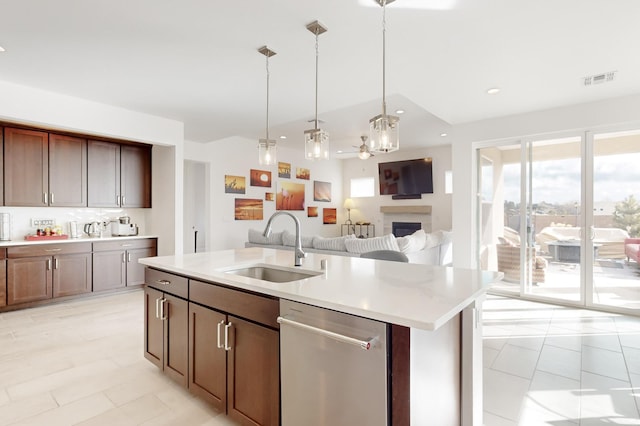 kitchen with sink, dark brown cabinets, a center island with sink, decorative light fixtures, and stainless steel dishwasher