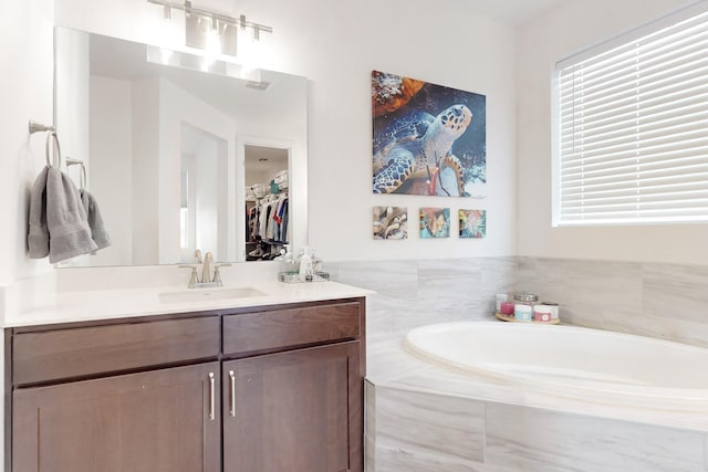 bathroom with vanity and tiled bath