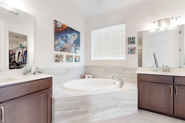 bathroom with vanity, a relaxing tiled tub, and tile patterned floors