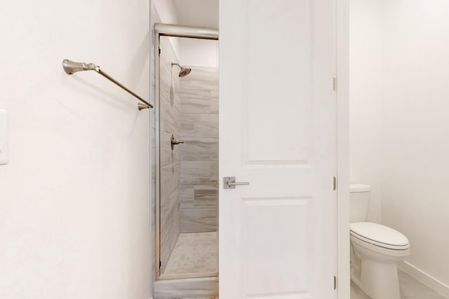 bathroom featuring a shower with shower door and toilet