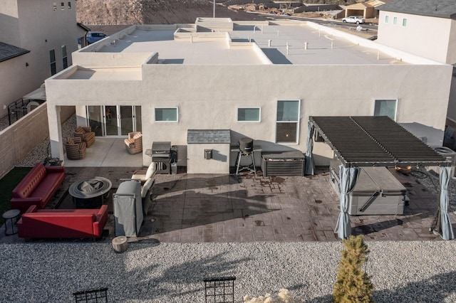 back of property with an outdoor kitchen, an outdoor fire pit, and a patio