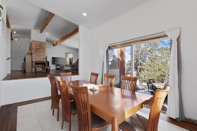 tiled dining space with lofted ceiling with beams and a fireplace