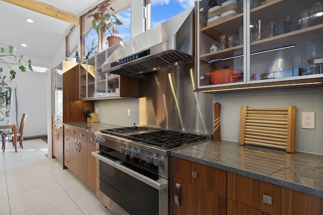 kitchen with backsplash, range with two ovens, extractor fan, and dark stone countertops