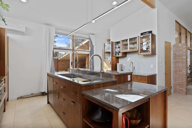 kitchen with a wall unit AC, sink, white dishwasher, a kitchen island with sink, and light tile patterned floors