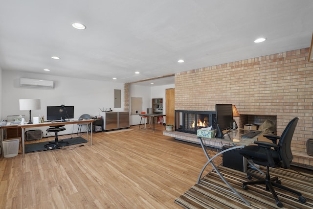 office space with a brick fireplace, light hardwood / wood-style floors, electric panel, and an AC wall unit