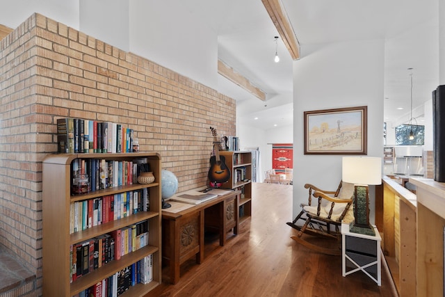 living area with beam ceiling, wood-type flooring, and brick wall