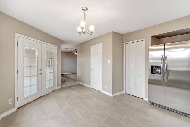 unfurnished dining area with french doors and a notable chandelier