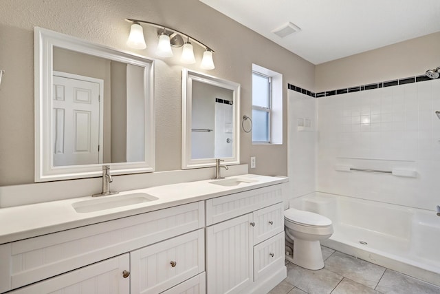 bathroom featuring tiled shower, tile patterned floors, vanity, and toilet