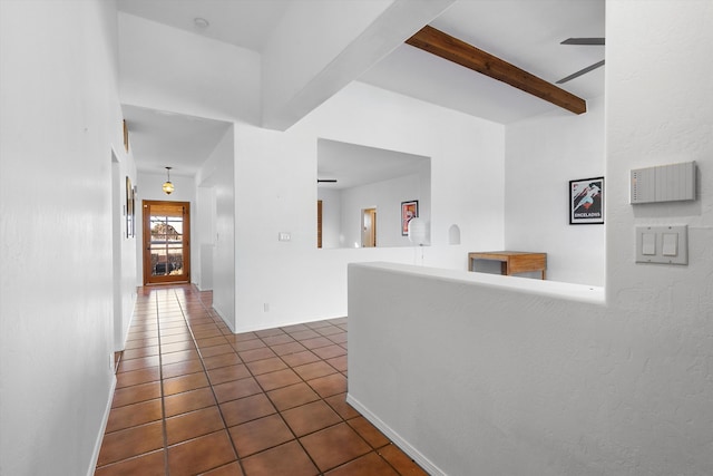 hall featuring dark tile patterned flooring and beam ceiling