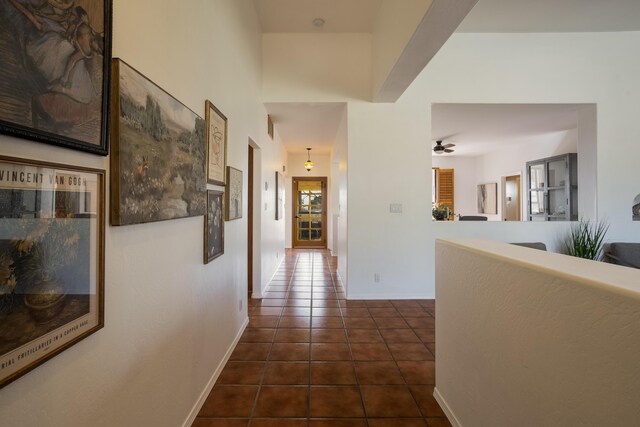 hall featuring baseboards and dark tile patterned floors