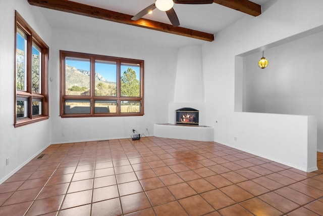 unfurnished living room featuring ceiling fan, a healthy amount of sunlight, a fireplace, and tile patterned floors