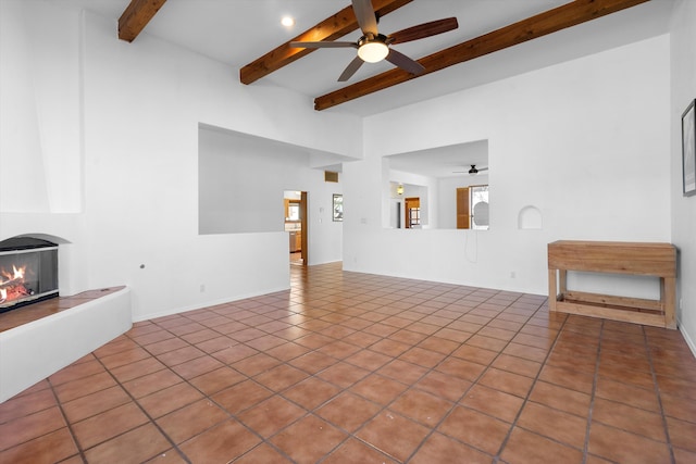 unfurnished living room featuring light tile patterned floors, ceiling fan, a large fireplace, and beamed ceiling