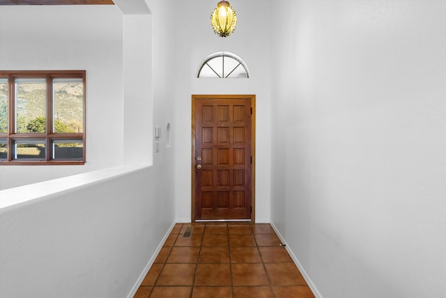 doorway with a high ceiling and dark tile patterned flooring