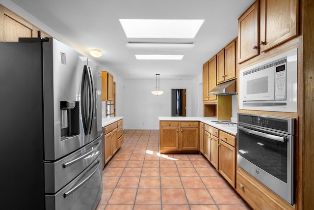 kitchen featuring decorative light fixtures, kitchen peninsula, a skylight, appliances with stainless steel finishes, and light tile patterned floors