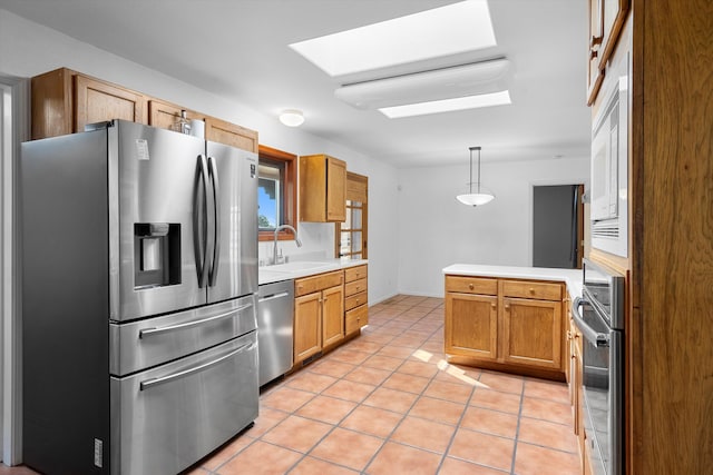 kitchen with hanging light fixtures, appliances with stainless steel finishes, sink, and light tile patterned flooring