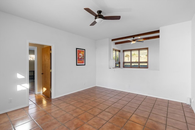 empty room featuring ceiling fan, tile patterned flooring, and beamed ceiling