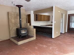 kitchen featuring a textured ceiling, ceiling fan, and a wood stove