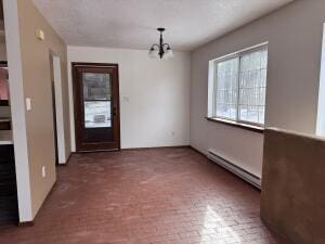 unfurnished dining area with a baseboard heating unit and a notable chandelier