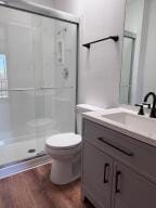 bathroom featuring wood-type flooring, toilet, vanity, and an enclosed shower