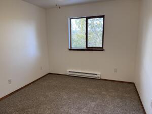 spare room with baseboard heating and dark colored carpet