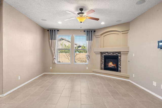 unfurnished living room with ceiling fan, a stone fireplace, and a textured ceiling