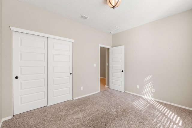 unfurnished bedroom with carpet floors, a closet, and a textured ceiling