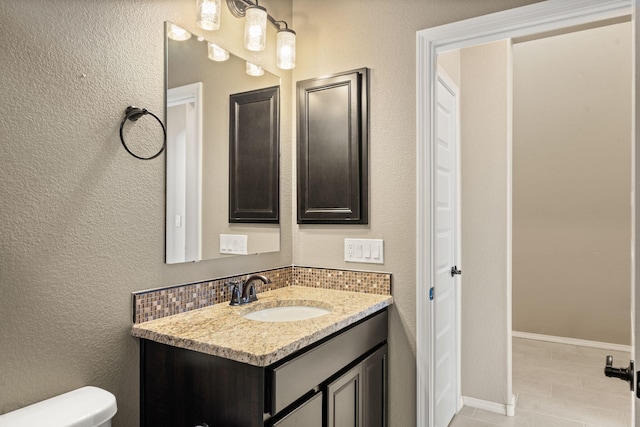 bathroom featuring tile patterned flooring, vanity, decorative backsplash, and toilet