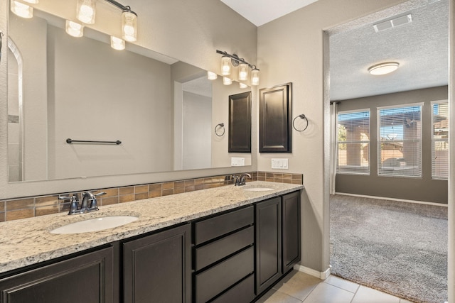 bathroom with a textured ceiling, decorative backsplash, tile patterned floors, and vanity