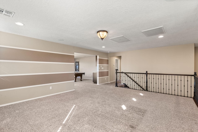 carpeted empty room with pool table and a textured ceiling