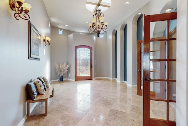 foyer featuring french doors, a notable chandelier, and a towering ceiling