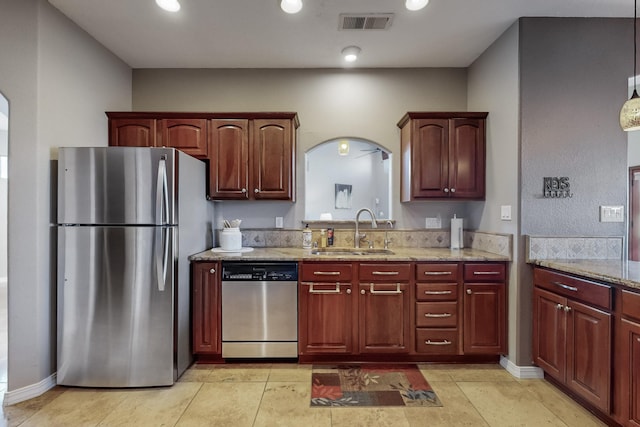 kitchen with sink, hanging light fixtures, light stone countertops, appliances with stainless steel finishes, and light tile patterned floors