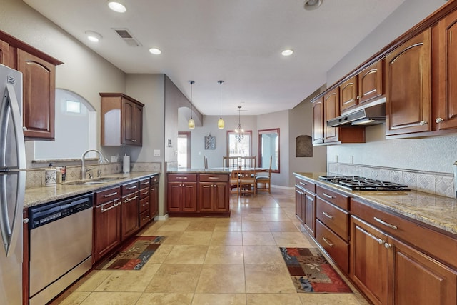 kitchen with decorative light fixtures, sink, appliances with stainless steel finishes, and light stone countertops