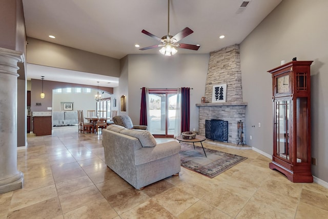 living room featuring a fireplace, ceiling fan with notable chandelier, a towering ceiling, and decorative columns