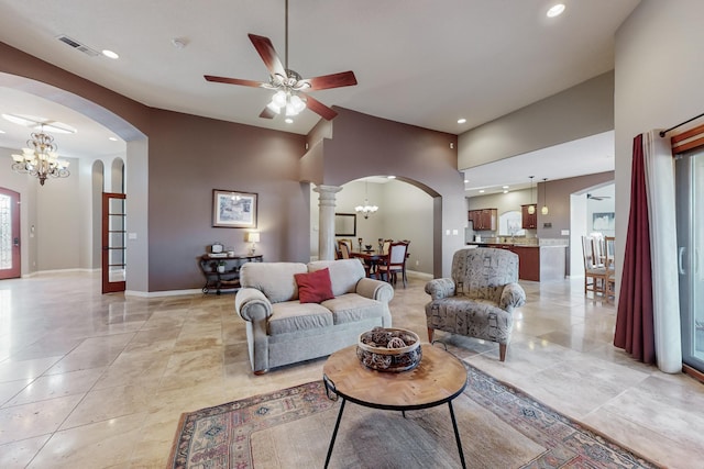 tiled living room with ceiling fan with notable chandelier, a high ceiling, and ornate columns